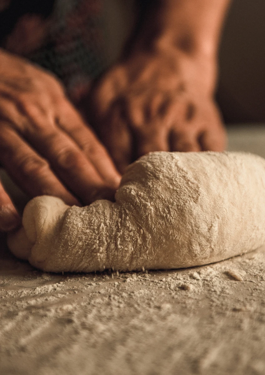 Hands kneading dough on floured countertop