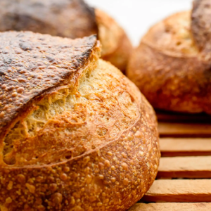 Crusty sourdough loaves on wooden cooling rack